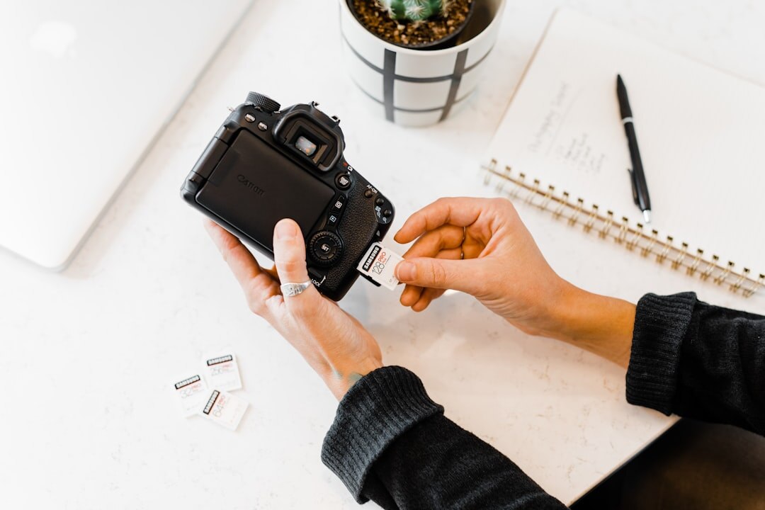 Photographer's hands reviewing contact sheets and camera on a wooden desk